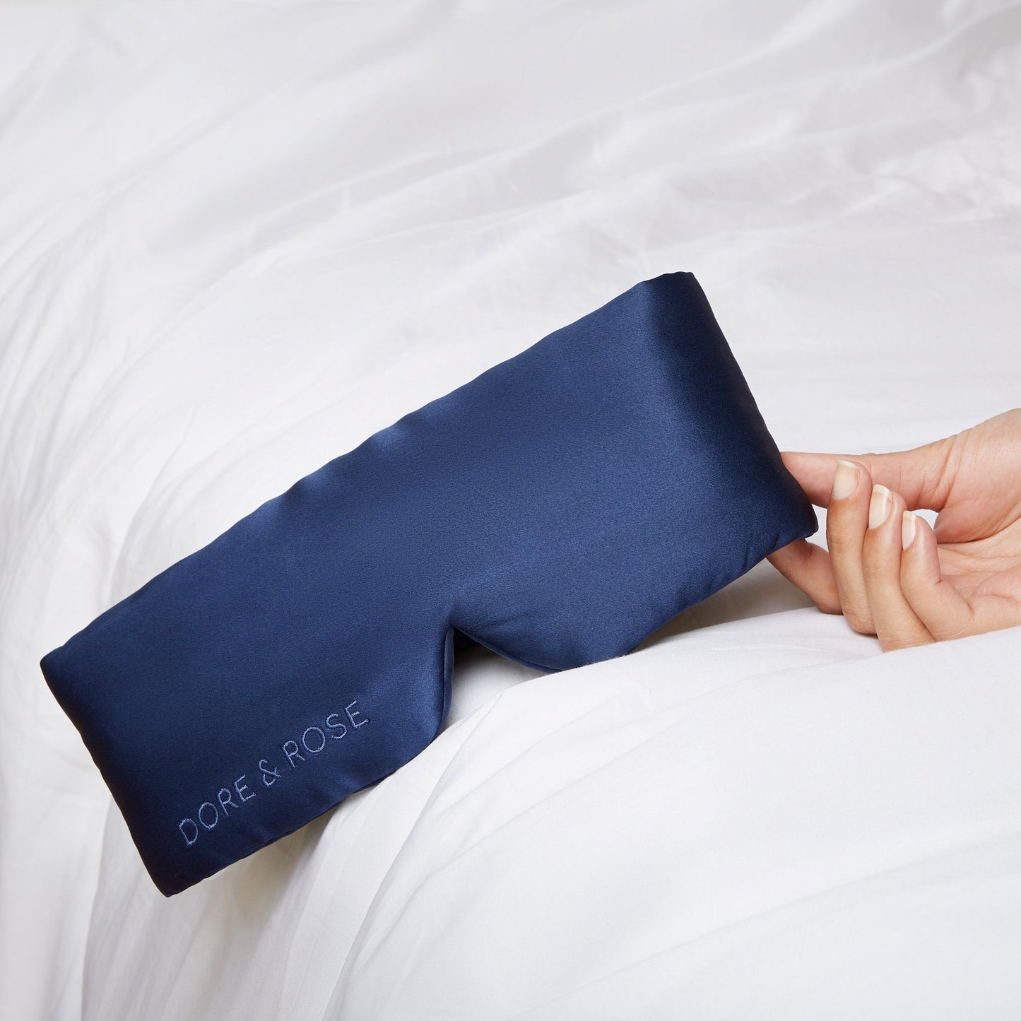 Hand of a woman holding a Silk Blue Sleeping Eyemask