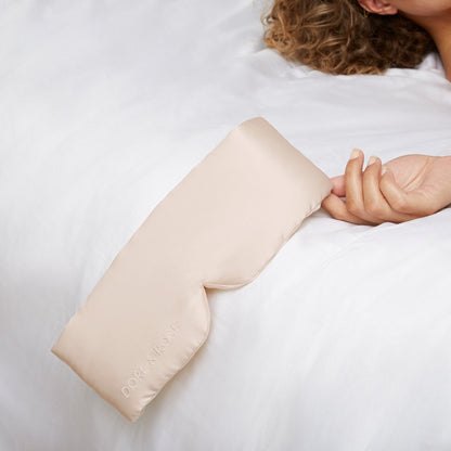 Hand of a woman holding a Silk Beige Sleeping Eyemask