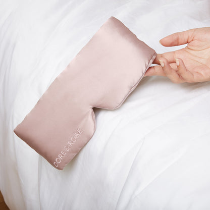 Woman's hand holding a Silk Pink Sleeping Eyemask